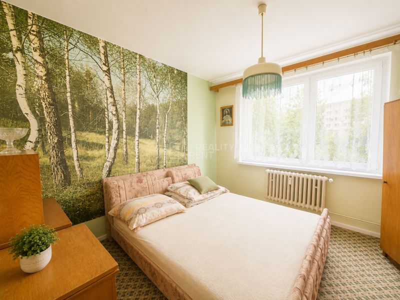 A bedroom in a 3-room apartment with natural wallpaper and simple furniture.
