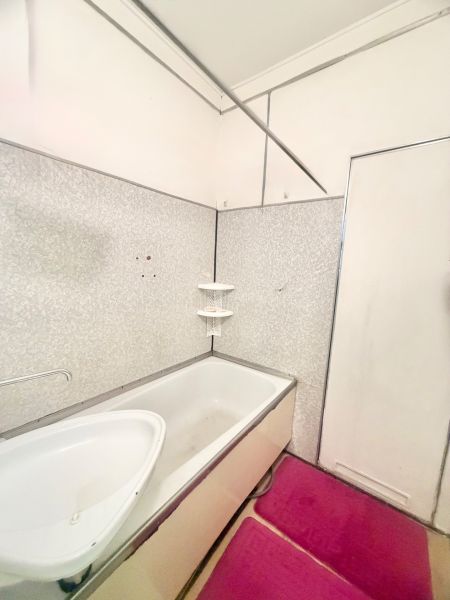 A bathroom in a 3-room apartment with a bathtub and mats on the floor.
