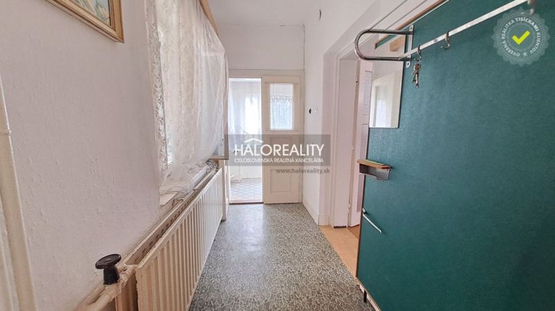 Interior of a family house with a hallway, radiator, and light curtains on the windows.
