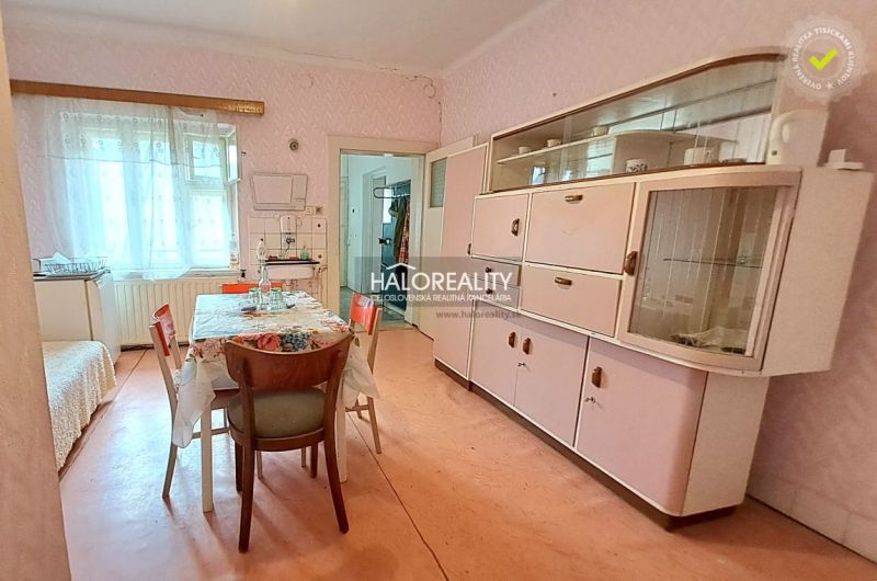 Dining room in a family house with retro furniture, a floral tablecloth, and a display cabinet.