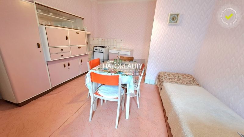 A kitchen in a family house with retro furniture and pink walls.