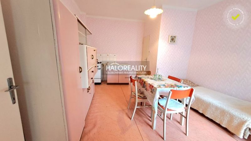 Pink kitchen with dining table and bed in a family house.