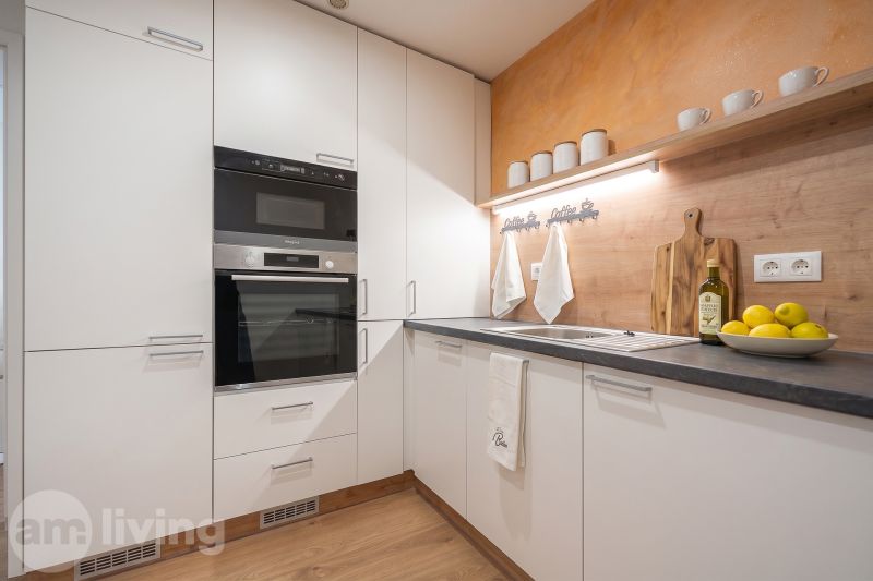 A kitchen in a family house with white cabinets, a stove, and a wooden-patterned floor.