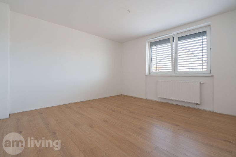 A room in a family house with white walls and a wooden decor floor.