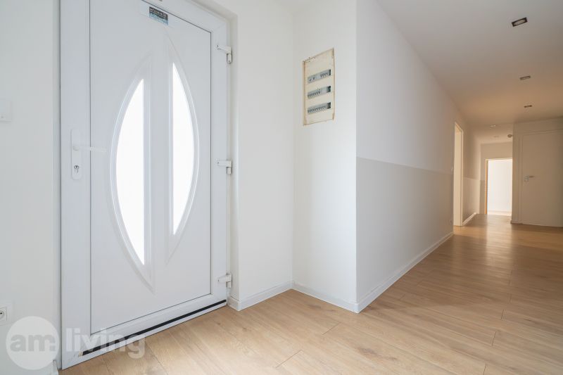 Entrance hallway in a family house with a wooden decor floor and white doors.