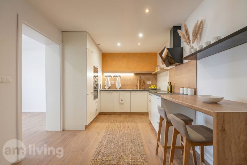 A kitchen in a family house with a bar counter and a wooden decor floor.