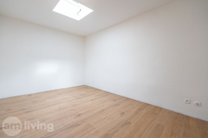 A room in a family house with a wooden decor floor and a skylight.