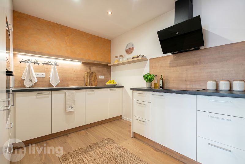 A kitchen in a family house with white cabinets, wooden decor, and citrus fruits on the shelf.