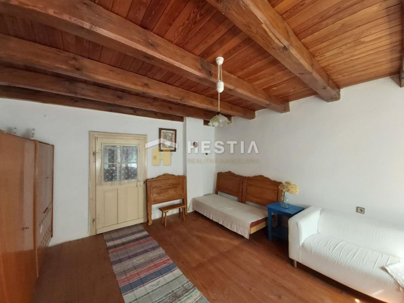 A room with a wooden ceiling, a floor with a wooden decor, and simple furniture.