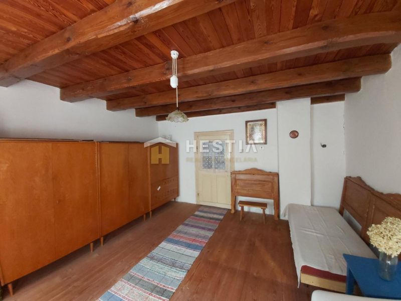 Interior with a wardrobe and a bed, floor with wooden decor, ceiling with wooden beams.