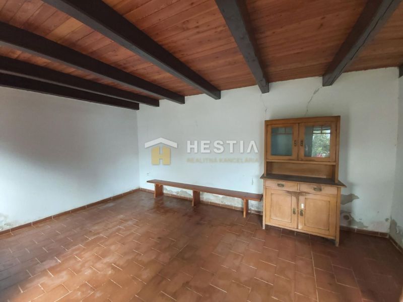 A room with a ceramic floor, a wooden beam ceiling, and a wooden display cabinet. Land - living.