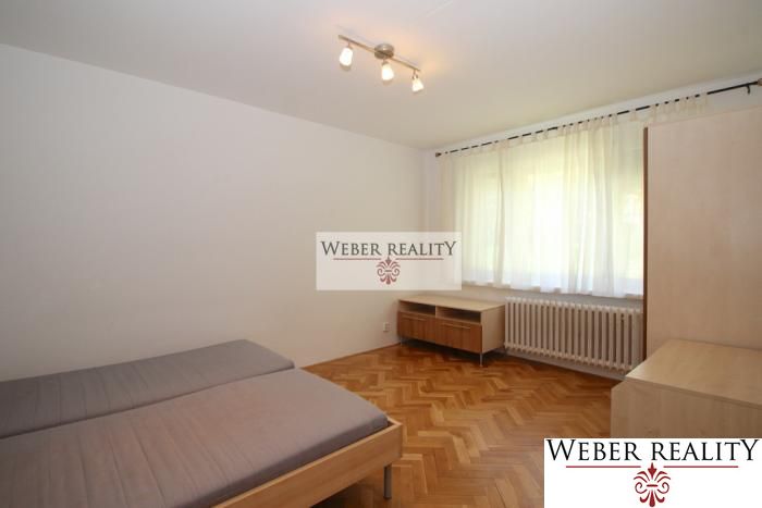 A bedroom in a studio apartment with a bed, furniture, and a wooden decor floor.