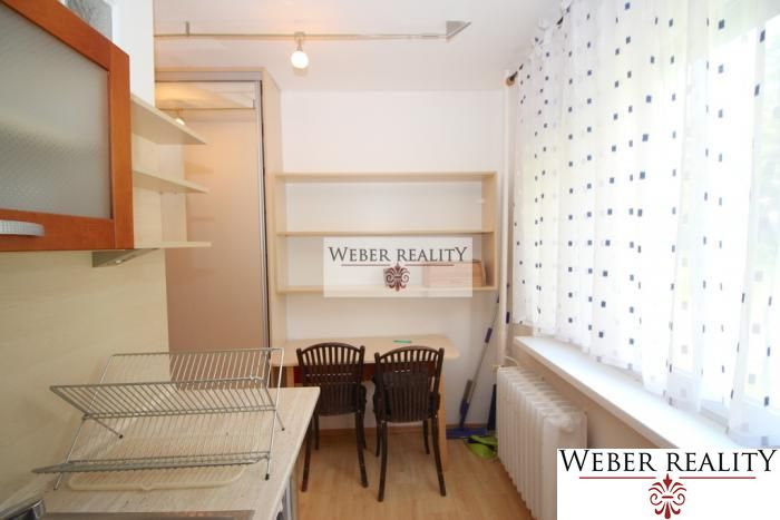 A kitchen in a one-room apartment with shelves, a table, and two chairs.