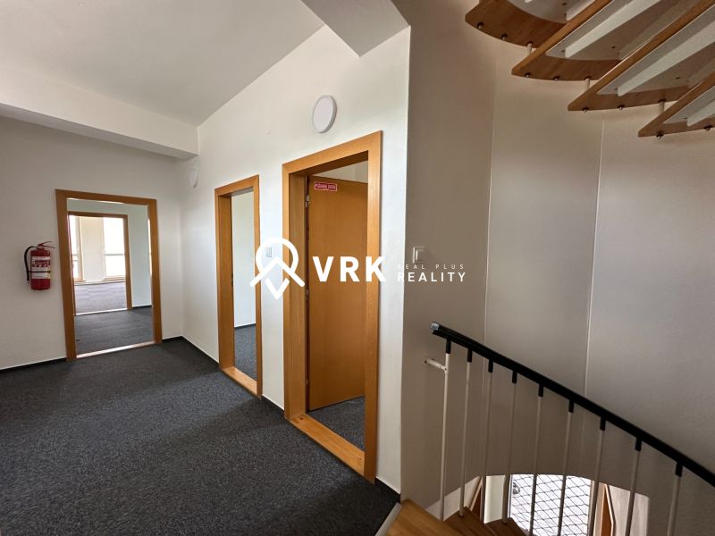 A corridor with a staircase in offices with a wood-decor floor and carpet.