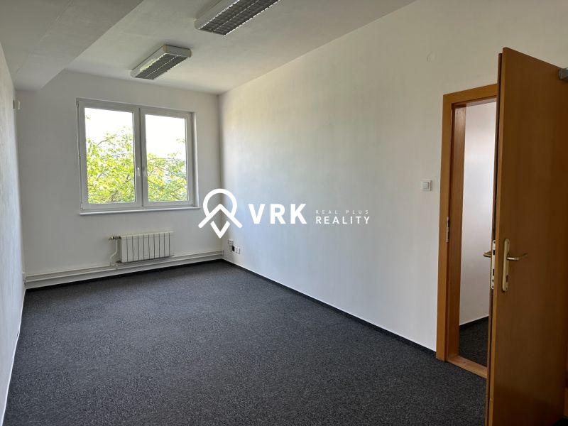 An empty office with a carpet and a window offers a simple solution for a workspace.
