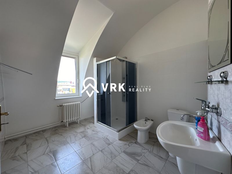Bathroom with a sink, shower, toilet, and bidet on a tiled floor.