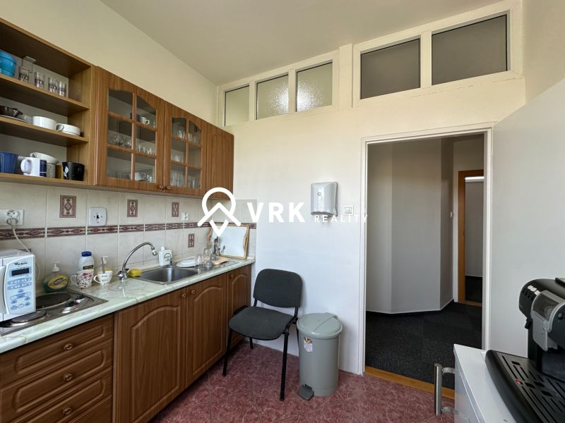 A kitchenette with a kitchen counter, open shelves, and appliances in offices.
