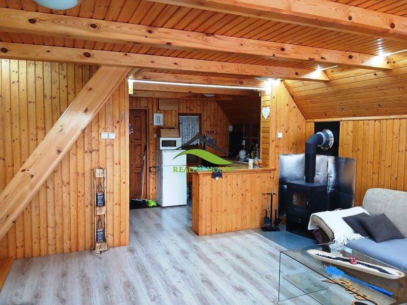 Interior of a cabin with a wood-patterned floor, an armchair, and a fireplace for a cozy atmosphere.