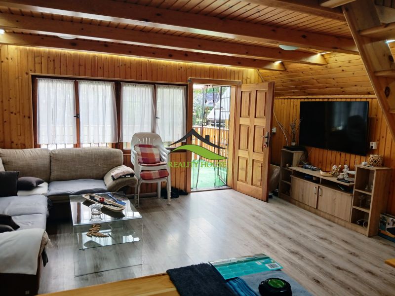 The interior of a cabin with a comfortable couch, television, and a wooden decor floor.