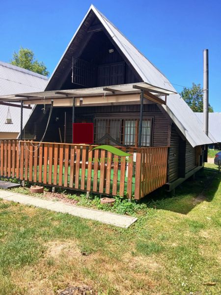 A cottage in Vinné with a wooden terrace and a small yard, surrounded by greenery.