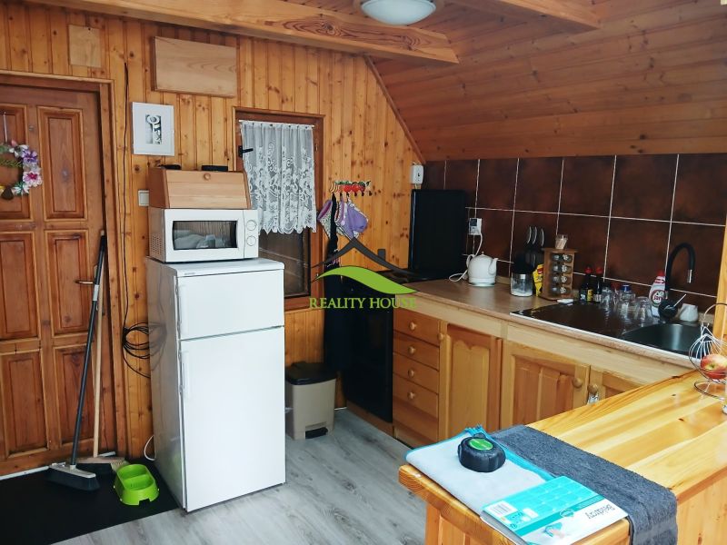 A kitchenette in a cabin with a wood-patterned floor, appliances, and wood paneling.