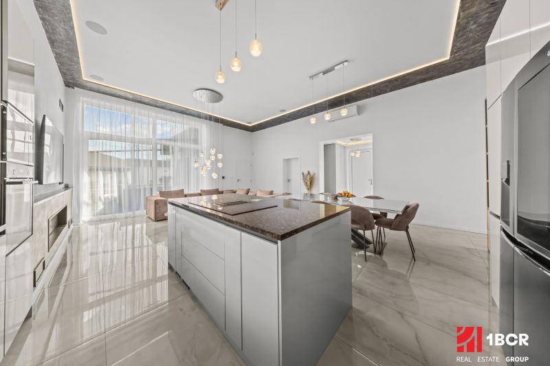 A spacious kitchen with an island and pendant lights in a family house.