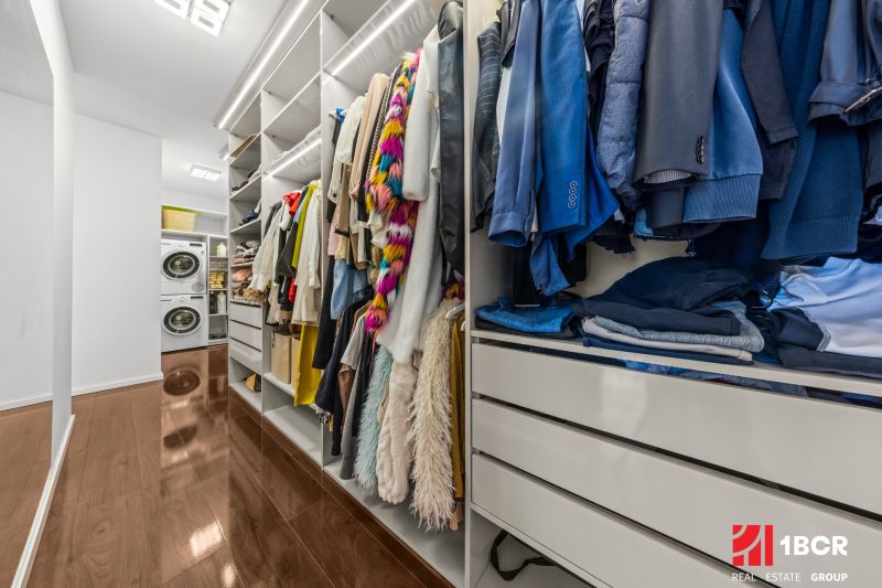 A wardrobe in a family house with a wooden decor floor and a washing machine with a dryer.