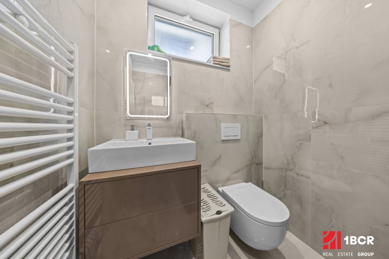 Bathroom in a family house with a sink, toilet, heating, and a mirror with lighting.