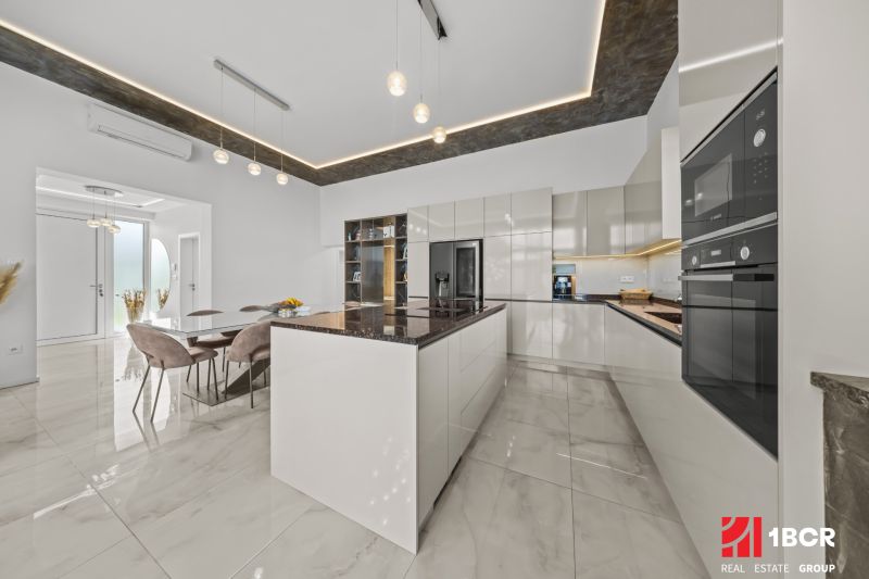 A kitchen in a family house with a marble floor and modern lighting.