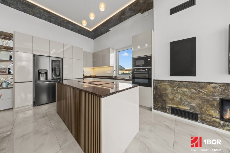 A spacious kitchen in a family house with modern furniture and a stone countertop.