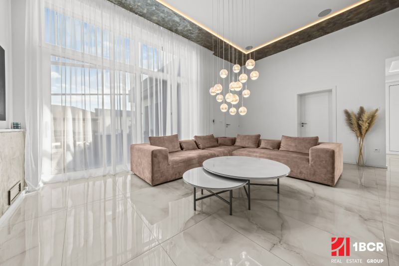 Living room in a family house with a light sofa, round tables, and a pendant light.