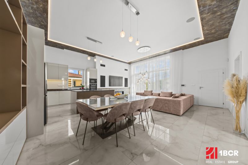 A space in a family house with a dining table and kitchen, wooden decor flooring.