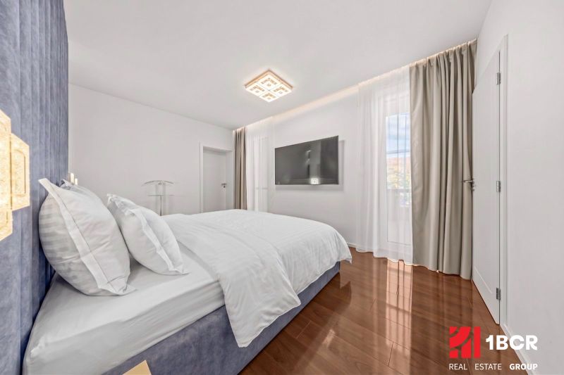 A bright bedroom in a family house with a TV and a wooden decor floor.