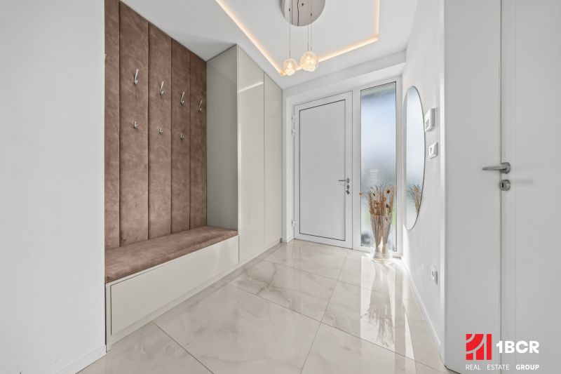 Entrance hallway in a family house with coat racks and comfortable seating on light tiles.