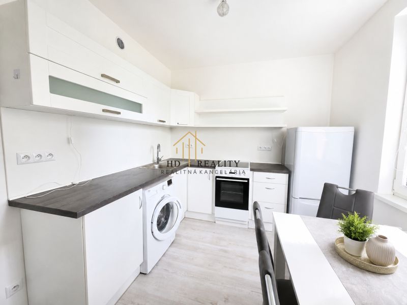A kitchen in a 2-room apartment with white cabinets and a wood-patterned floor.