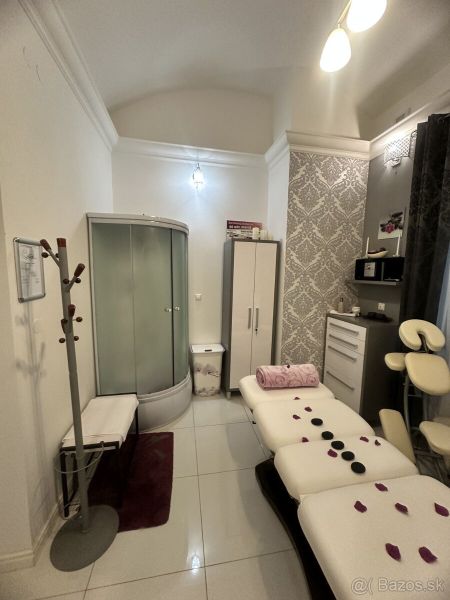 Massage room with a couch, shower corner, and decorative wallpaper in commercial premises.