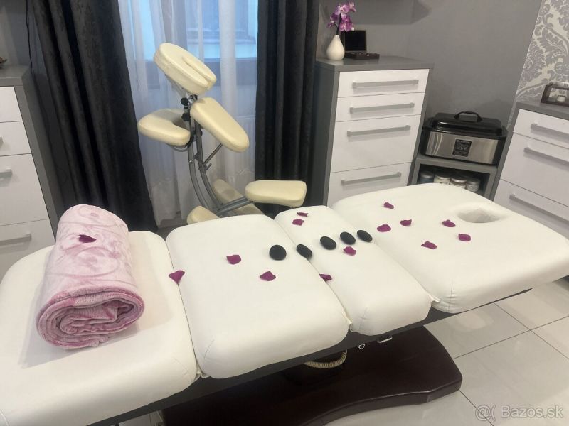 Massage table with towel, flower petals, and lava stones in commercial premises.