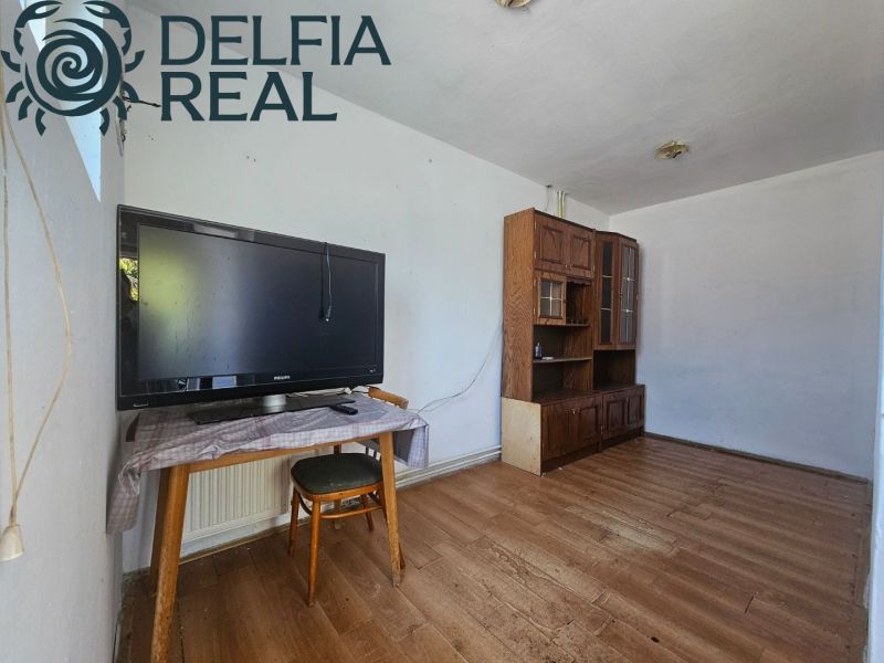 A room in a cottage with a TV on the table, a floor with a wooden decor.
