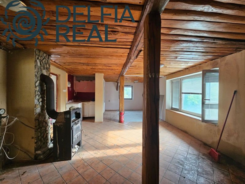 The interior of the cottage with tiled stoves, a wooden ceiling, and large windows.