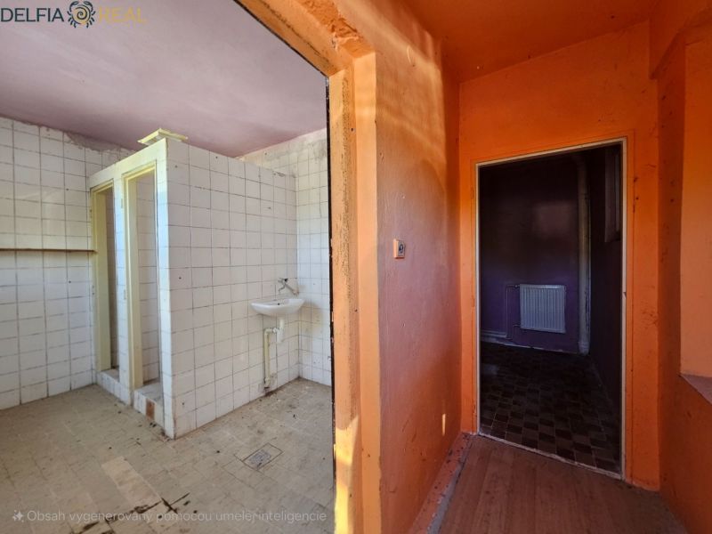 A bathroom in a cabin with tiles and a sink, next to an orange hallway.