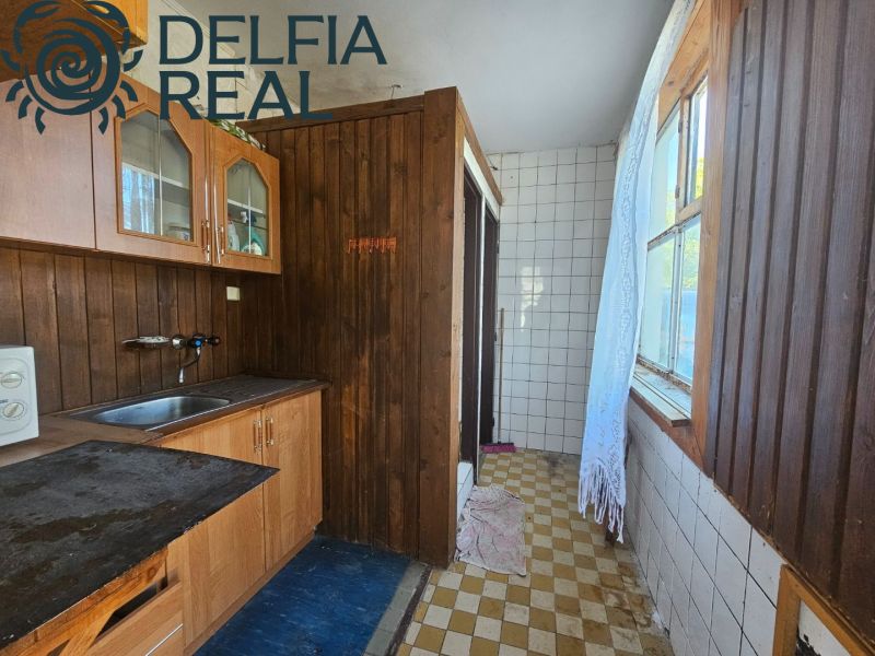 Interior of a cabin with a wooden kitchen unit and a tiled wall.