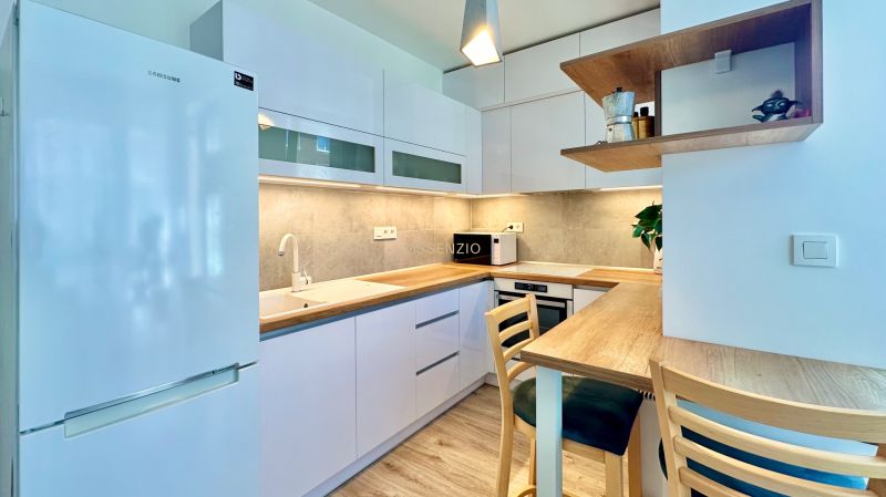 A kitchen in a 2-room apartment with a wooden decor floor and white furniture.