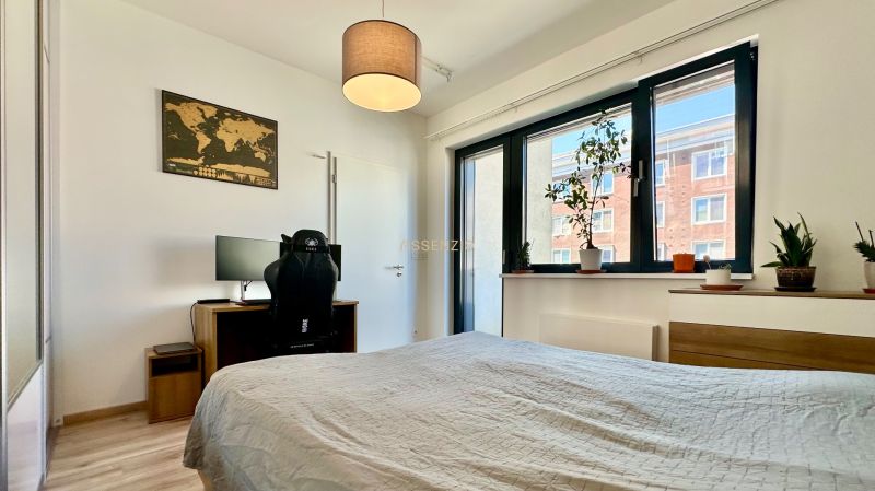 A bedroom in a 2-room apartment with a desk and plants on the windowsill.