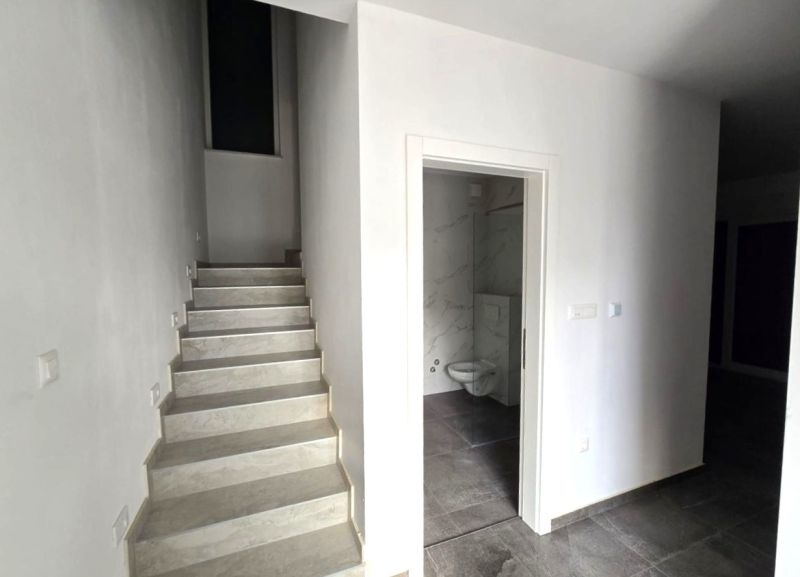 Interior of a family house with marble stairs and a bathroom with a black floor.