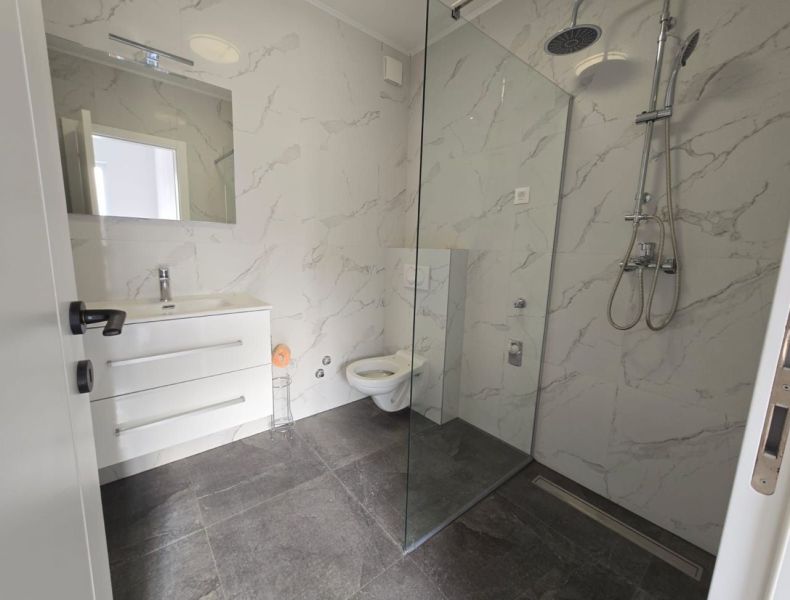 A bathroom in a family house with modern tiles and a shower enclosure.