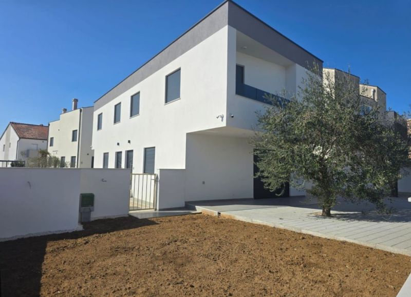 A family house in Vrsi with a white facade and an adjacent plot.