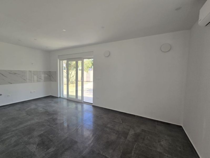 Living room in a family house with dark tiles and sliding doors to the terrace.