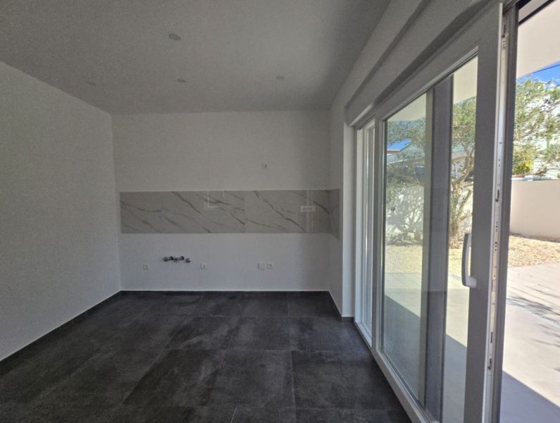Interior of a family house with tiles, white walls, and large glass doors.