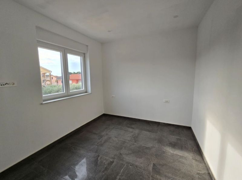 Interior of a room in a family house with white walls and a dark floor.