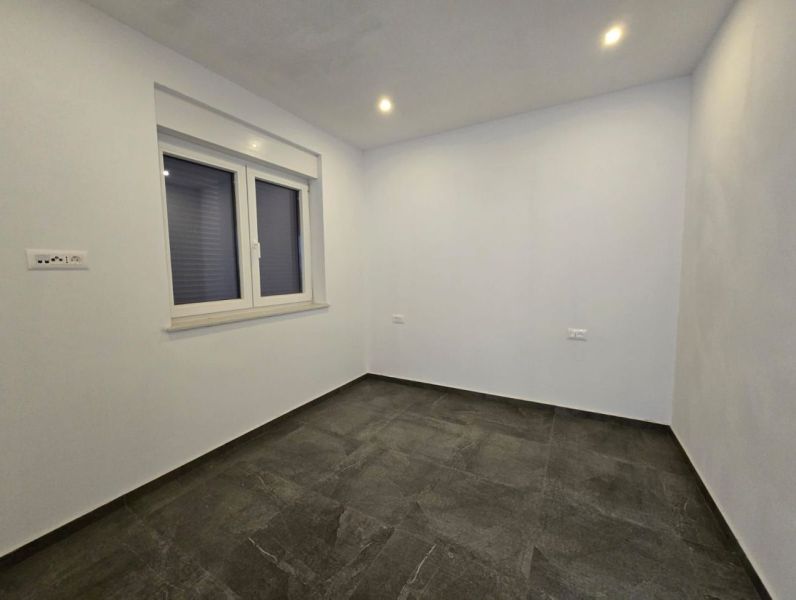 A room with white walls and a dark floor in a family house.